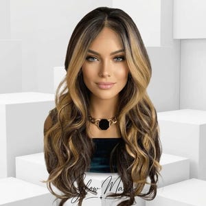 May include: A long, wavy wig with dark brown and blonde highlights. The wig is styled with a side part and cascading curls. The model is wearing a gold necklace with a black pendant. The background is a white, geometric design.