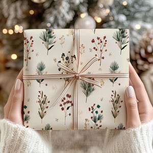 Elegant neutral tone Christmas wrapping paper decorated with botanical branches, ideal for festive packaging.