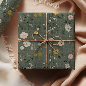 May include: A wrapped gift with floral patterned wrapping paper in shades of green, white, yellow, and pink. The gift is tied with twine. A roll of matching wrapping paper is visible in the background.