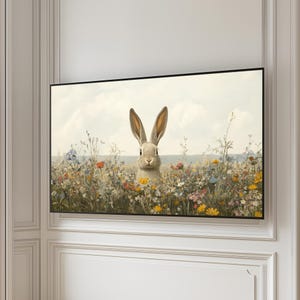 K&ouml;nnte beinhalten: Ein wei&szlig;es Kaninchen mit braunen Augen sitzt in einem Feld voller bunter Wildblumen. Das Kaninchen schaut direkt auf den Betrachter.