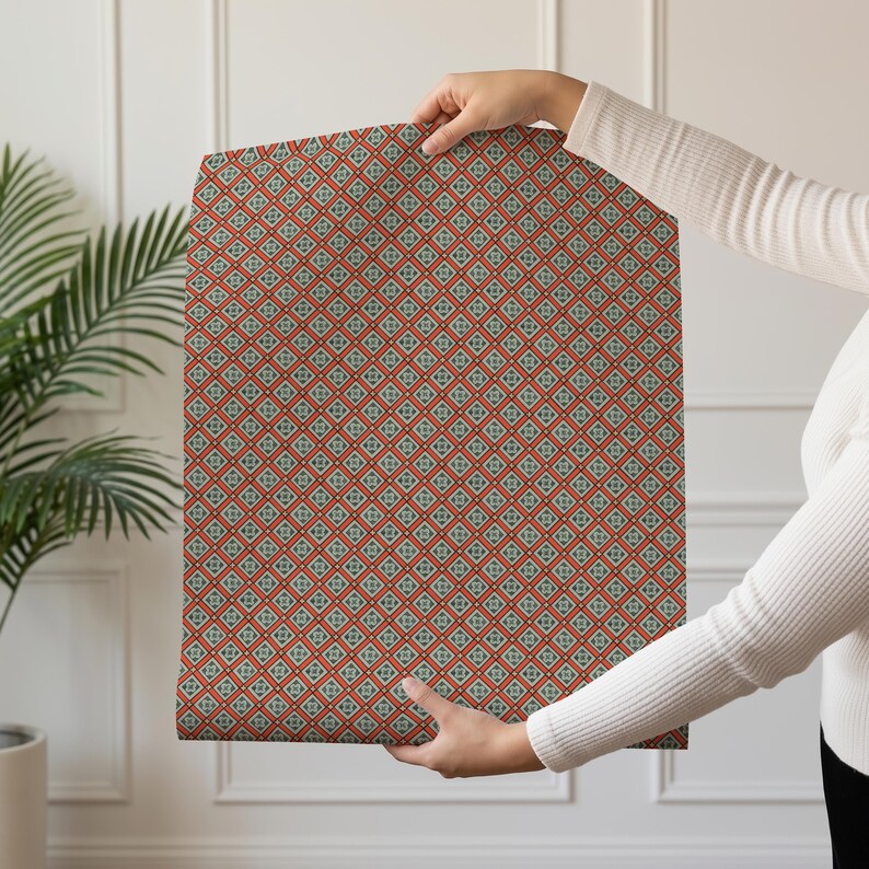 May include: A rectangular sheet of wrapping paper featuring a repeating geometric pattern of orange diamond shapes outlined in dark lines, each containing a small central floral motif in shades of teal, white, and yellow against a light background.