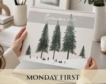 May include: A 2027 wall calendar titled Calendar 2027 The Magic of Four Seasons, featuring a watercolor illustration of evergreen trees in a snowy landscape with small figures sledding and walking, bound with a white spiral wire at the top.
