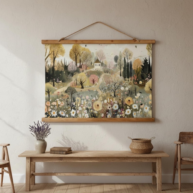 May include: A landscape print featuring a whimsical scene of a hillside with a white house, trees, and wildflowers. The artwork is displayed on a wooden frame with a hanging rope. The color palette includes soft greens, yellows, and pinks.