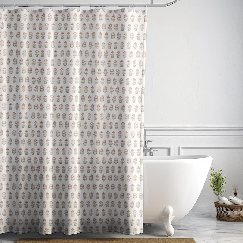 May include: A cream-colored shower curtain with a repeating pattern of small, stylized floral motifs in shades of brown and peach. The curtain is hanging in front of a white bathtub in a bathroom setting.
