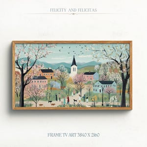 May include: A framed painting depicting a quaint village scene with a church steeple, houses, and people walking along a path lined with blooming trees. The painting is in a light wood frame and has a light blue background.