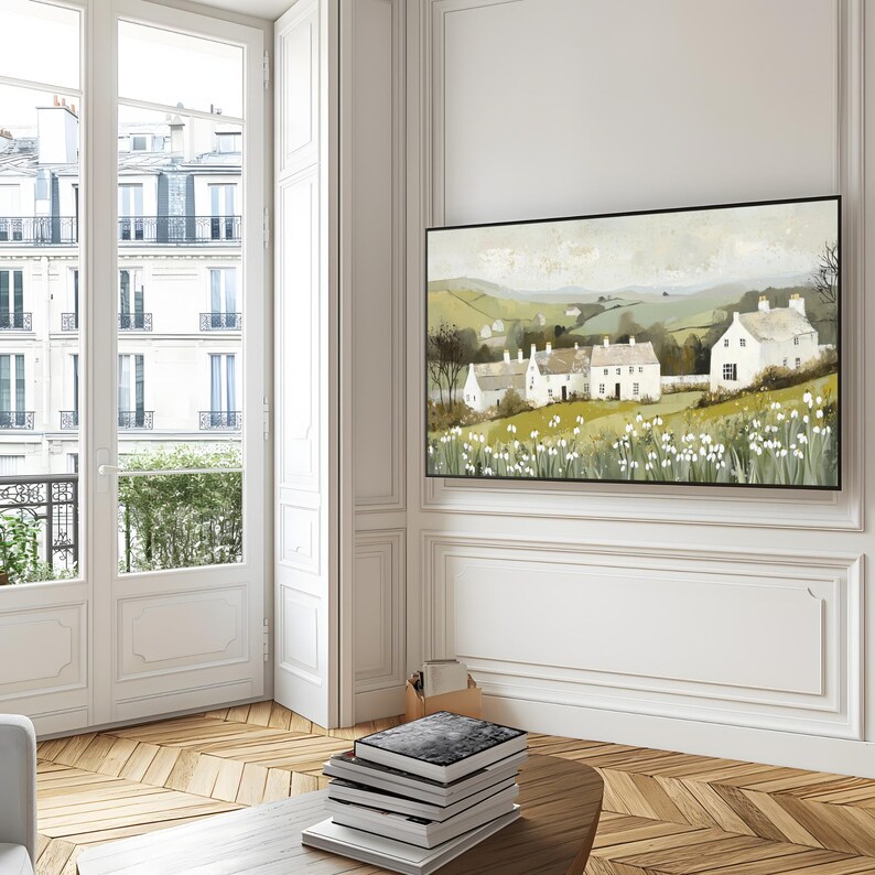 May include: A painting depicting a white farmhouse nestled amongst rolling green hills. The farmhouse is surrounded by a field of white flowers. The painting is framed in black.