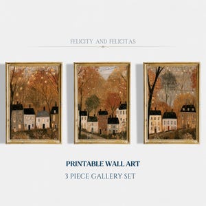 May include: A three-piece gallery set of printable wall art titled FELICITY AND FELICITAS. Each vertical print features a row of houses nestled among autumn trees with string lights hanging above. The colour palette includes warm orange, brown, and grey tones.