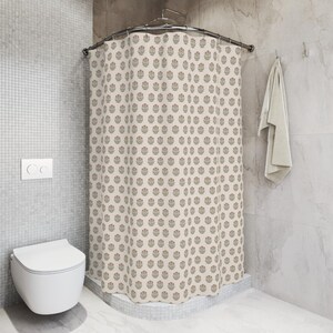 May include: A beige shower curtain with a repeating floral pattern in red, green, and brown. The curtain is hanging in a bathroom with a white toilet and a towel. The walls are tiled in a light gray color.