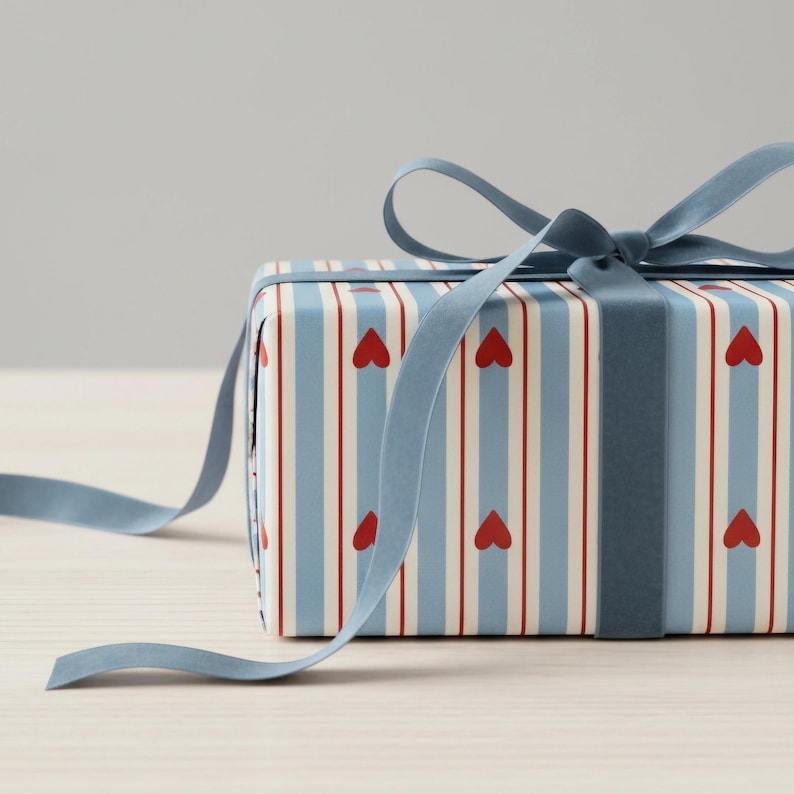 May include: A wrapped gift box with a blue ribbon. The gift wrap features a pattern of red hearts and vertical stripes in blue and white. The blue ribbon is tied in a bow.