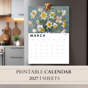 May include: A 2027 wall calendar for the month of March featuring a floral illustration of white and yellow daffodils in a blue and white patterned vase, topped with a small brown dog magnet on a gray refrigerator surface.