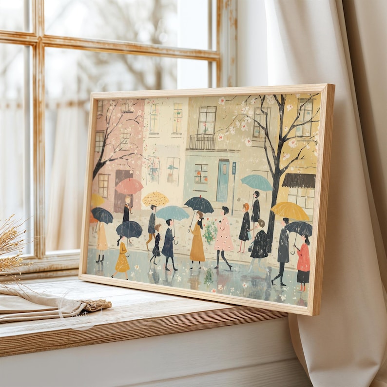 May include: A framed illustration of people walking down a street with umbrellas in a light rain. The buildings are painted in pastel colors with pink and white flowers on the trees.
