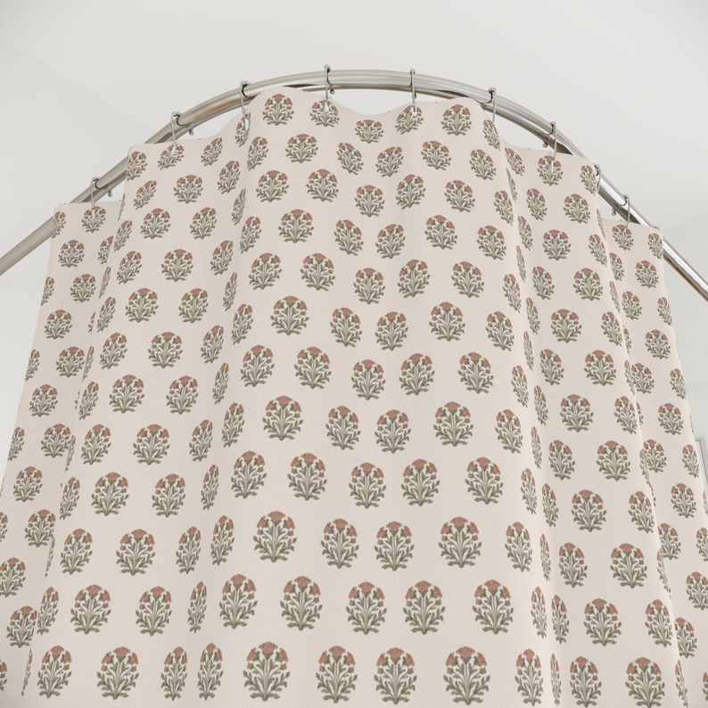 May include: A shower curtain with a repeating floral pattern. The flowers are a muted red-orange color with green leaves, set against a cream-colored background. The curtain hangs from a curved, silver-colored shower rod.