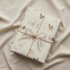 Peut inclure: Un cadeau emballé avec du papier crème orné d'un motif répété de poulets et de fleurs sauvages à l'aquarelle. Le paquet est noué avec de la ficelle, formant un nœud. Le fond est un tissu neutre et texturé.