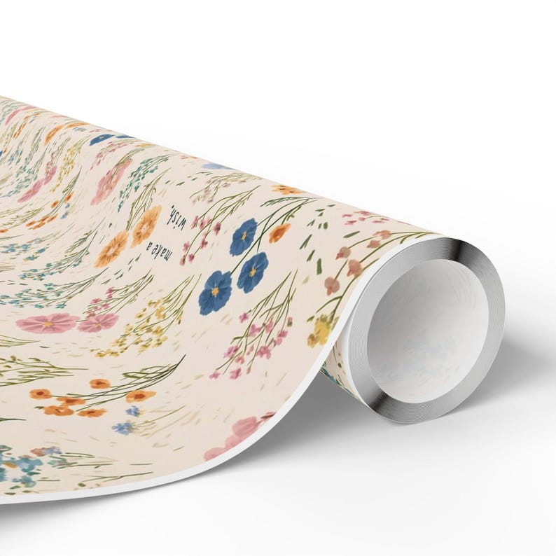 May include: Rolled floral wrapping paper with a cream background. The paper features a repeating pattern of colourful flowers in shades of blue, pink, yellow, and orange. The words "make a wish" are printed on the paper.