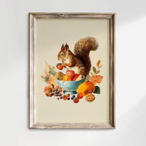 Puede incluir: Una lámina de arte enmarcada que muestra una ardilla marrón sosteniendo una bellota, situada sobre un cuenco azul claro lleno de frutas, nueces y hojas de otoño. La composición incluye manzanas rojas, cítricos naranjas, bayas y nueces.