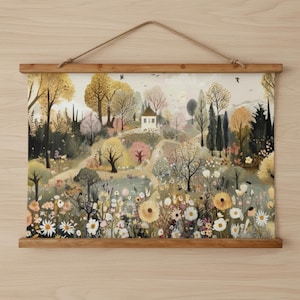 May include: A landscape art print featuring a serene countryside scene with a small white house, trees, and a variety of flowers. The print is displayed on a wooden frame and suspended by a natural rope.