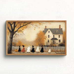 Op de afbeelding: Een ingelijste horizontale kunstprint met een groep kinderen in Halloween-kostuums, waaronder spoken en heksen, die langs een wit hek lopen voor een groot huis met herfstbomen en een pompoen op de grond.
