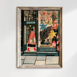 May include: A framed art print depicting a storefront with an OPEN sign. A figure in a red coat and red boots walks out carrying shopping bags. The window display features a blue star, a pine branch, a toy train, and a nesting doll.