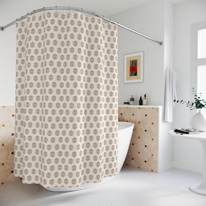 May include: Cream-colored shower curtain with a repeating floral pattern in shades of brown and red. The curtain hangs from a curved, silver-colored shower rod. The bathroom has a white tub and walls, with a small framed artwork.