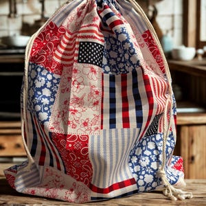 May include: A drawstring bag featuring a patchwork design with red, white, and blue patterns. The fabric displays various motifs including paisley, floral prints, stripes, checkered squares, and a section with white stars on a dark blue background.