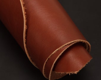 May include: A close-up of a rolled piece of brown leather with a slightly frayed edge.