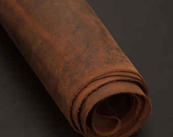 May include: A roll of brown leather with a distressed finish. The leather is rolled up tightly, showing the texture and grain of the material.