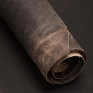 May include: A rolled up piece of dark brown leather with a distressed, worn look.