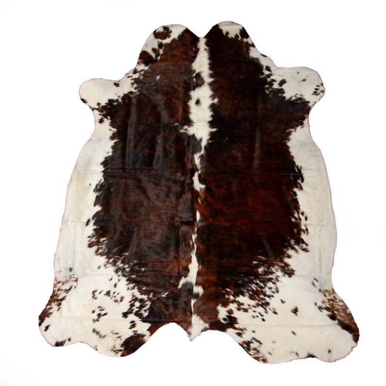 May include: A brown and white cowhide rug with a patchwork pattern. The rug is made of natural cowhide and has a soft, luxurious feel.
