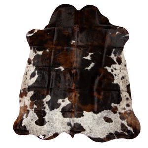 May include: A brown, black, and white cowhide rug with a natural, irregular shape. The hide has a patchwork pattern of different shades of brown and black, with white spots scattered throughout.
