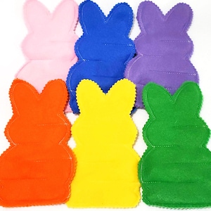 May include: Six colorful felt bunny shapes in pink, blue, purple, orange, yellow, and green. Each bunny has a scalloped edge and stitched details, perfect for Easter crafts or decorations.