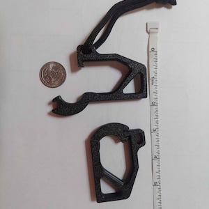 Puede incluir: Juego de herramientas múltiples de metal negro con un abrebotellas, un mosquetón y un cordón. El juego incluye una moneda para comparar el tamaño y una regla.