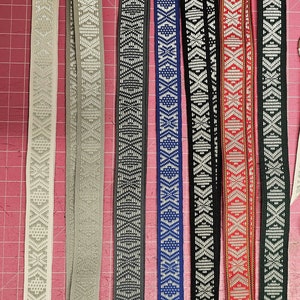 Puede incluir: Ocho cordones diferentes con patrones y clips giratorios plateados. Los cordones son blancos, grises, negros, azules, rojos y verdes con patrones geom&eacute;tricos.