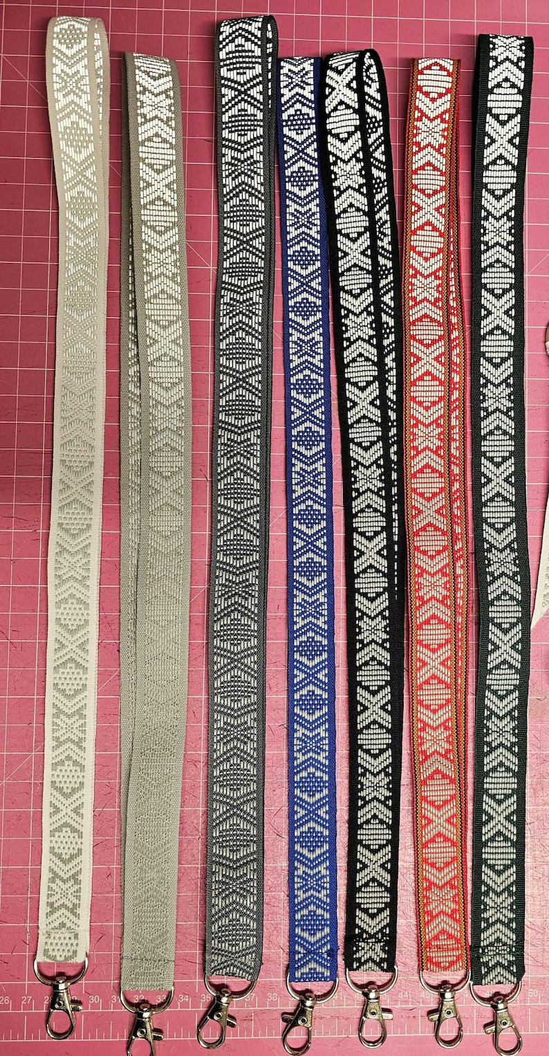 Puede incluir: Ocho cordones diferentes con patrones y clips giratorios plateados. Los cordones son blancos, grises, negros, azules, rojos y verdes con patrones geom&eacute;tricos.