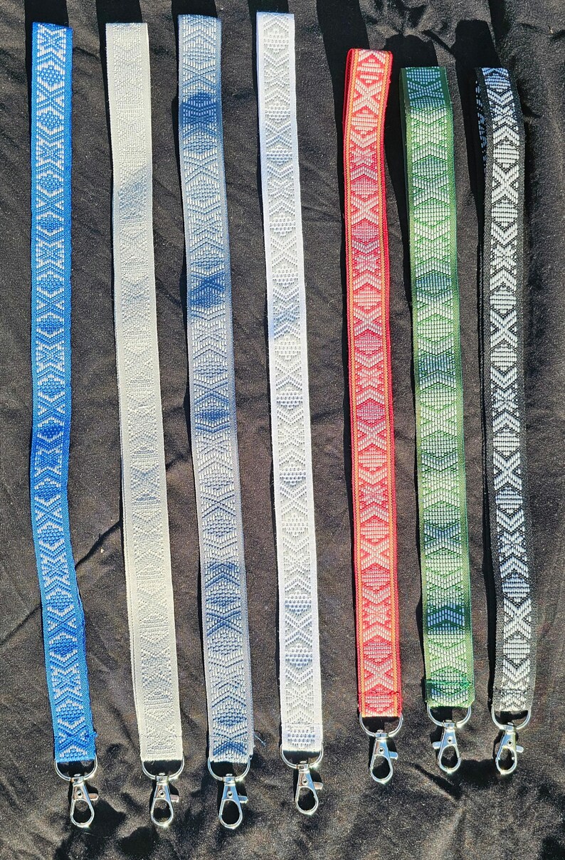 Puede incluir: Ocho cordones tejidos de colores con llaveros plateados. Los cordones presentan un patr&oacute;n geom&eacute;trico con detalles blancos. Los colores son azul, blanco, azul claro, blanco, rojo, verde y negro.