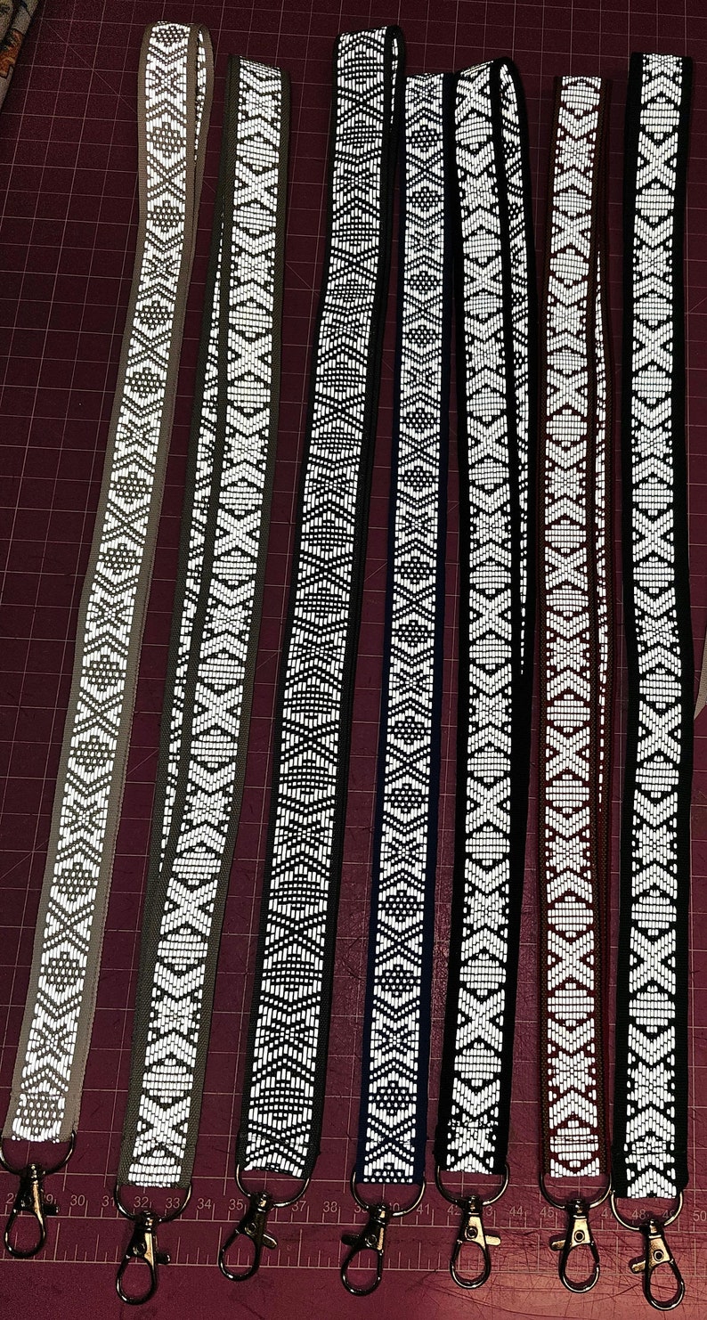 Puede incluir: Seis llaveros reflectantes con fondos de colores diferentes y un patr&oacute;n geom&eacute;trico blanco. Cada llavero tiene un cierre de metal plateado.