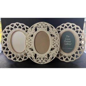 May include: Three oval-shaped cream-colored picture frames. Two frames feature a heart-shaped cutout border, while the center frame has an ornate scrollwork design. The right frame contains text reading The Lenox Portrait Gallery for your 3.5x5 photograph.