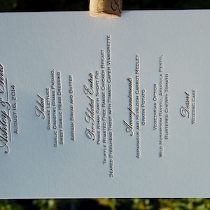 May include: A light blue wedding menu card with the names Ashley & Chris and the date August 16, 2014. The menu includes salad, pre-selected entree, accompaniments, and dessert options. The venue is St. Regis Deer Valley.