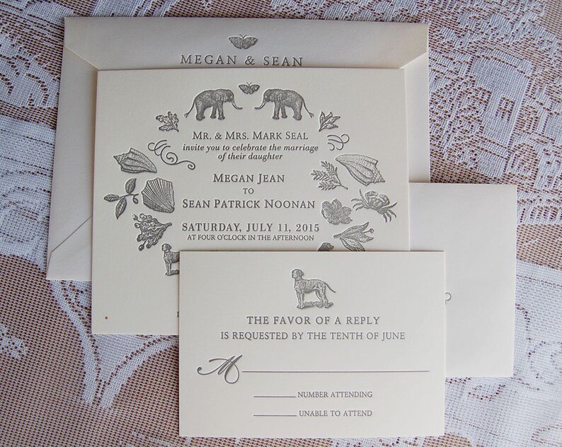 May include: Cream-colored wedding invitation suite with an envelope, invitation, and RSVP card. The invitation features the names "Megan & Sean" and details of the wedding, including the date, time, and names of the couple. Decorative illustrations include elephants, shells, and a dog.