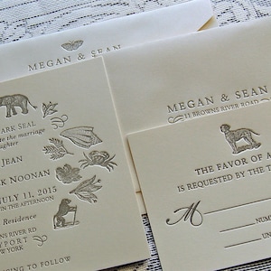 May include: Ivory wedding invitations with embossed details. The invitations feature the names "Megan & Sean" and include illustrations of animals and foliage. The RSVP card has a dog illustration.