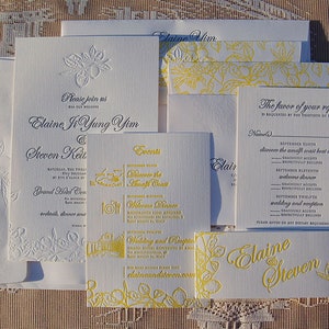 May include: A collection of white wedding stationery with embossed floral designs and yellow accents. Includes invitations, reply cards, and place cards. The text includes names, dates, and event details.