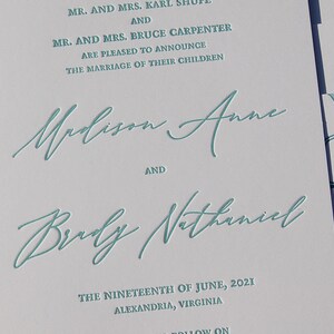 May include: Wedding invitation with teal script text on white paper. The text includes names, the date, and location: Alexandria, Virginia. The invitation also features a map graphic.
