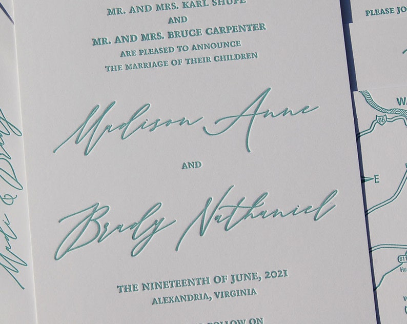 May include: Wedding invitation with teal script text on white paper. The text includes names, the date, and location: Alexandria, Virginia. The invitation also features a map graphic.