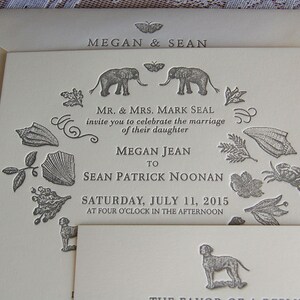 May include: Ivory wedding invitation with embossed details. The invitation features the names "Megan & Sean" at the top, and the names of the bride and groom. The invitation includes decorative elements like elephants, butterflies, and botanical illustrations.