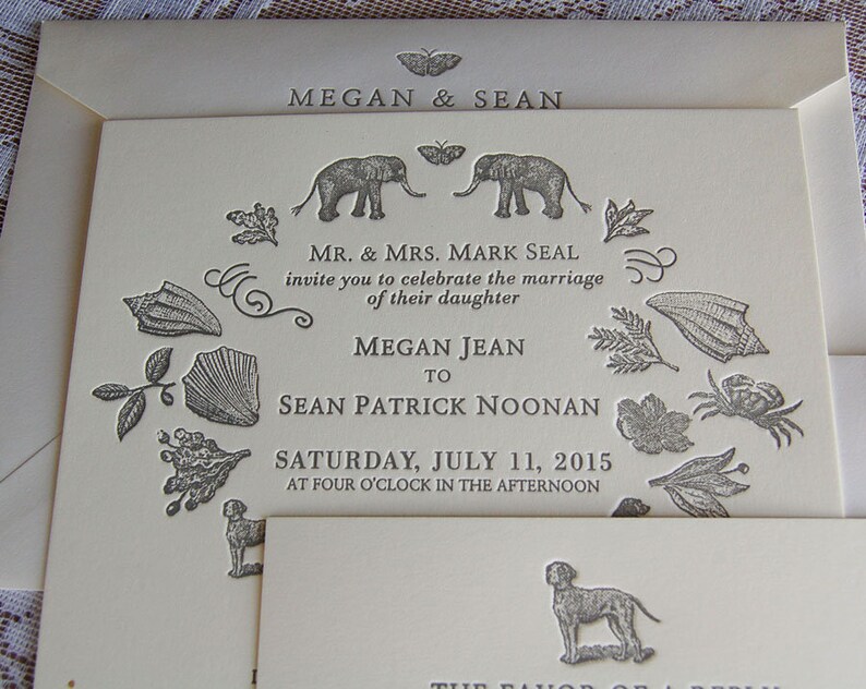 May include: Ivory wedding invitation with embossed details. The invitation features the names "Megan & Sean" at the top, and the names of the bride and groom. The invitation includes decorative elements like elephants, butterflies, and botanical illustrations.