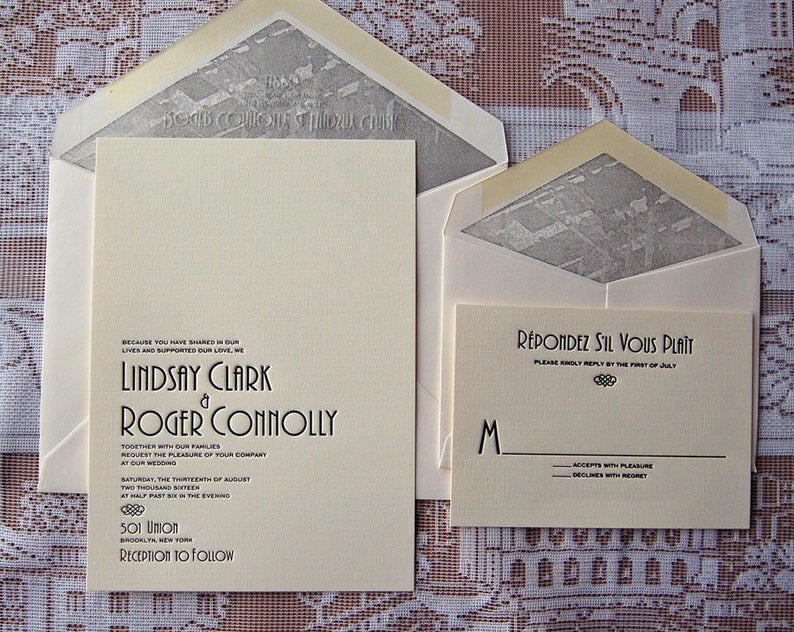 May include: Cream-colored wedding invitation suite with matching envelopes. The invitation features the names Lindsay Clark and Roger Connolly, along with wedding details. The RSVP card reads "R&eacute;pondez S'il Vous Pla&icirc;t". The envelopes have a gray patterned interior.