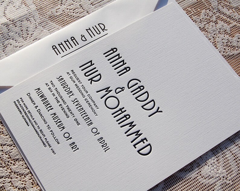 May include: A white wedding invitation with black text, featuring the names "Anna & Nur" on the envelope and the invitation. The invitation includes the names "Anna Gaddy & Nur Mohammed", date, time, and location: Milwaukee Museum of Art.
