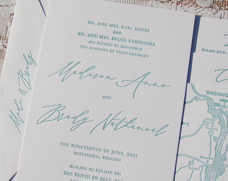 May include: White wedding invitation with teal script. The invitation announces the marriage of Madison Anne and Brady Nathaniel, with the date and location in Alexandria, Virginia. The invitation also includes a map.