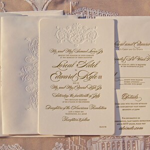 May include: Elegant ivory wedding invitation suite with gold foil lettering and embossed floral details. Includes invitation, RSVP, and details cards. Features the names Loreal and Edward.