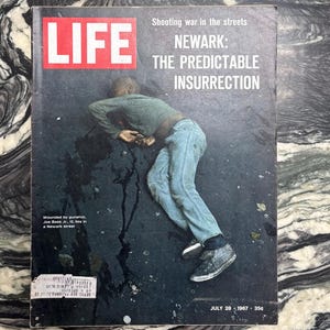 May include: A vintage LIFE magazine cover featuring a photograph of a person lying on the ground. The cover text reads "Shooting war in the streets: Newark: The Predictable Insurrection." The magazine is dated July 28, 1967.