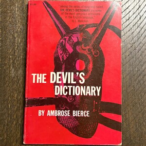 May include: Vintage paperback book titled "The Devil's Dictionary" by Ambrose Bierce. The cover is red with a black and pink illustration of a horned figure. Includes a quote by H.L. Mencken. The price is $1.00.